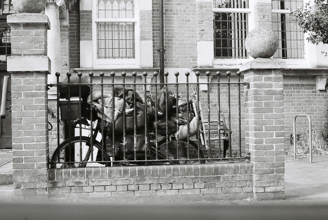 Bicycle parked behind fence in black and white