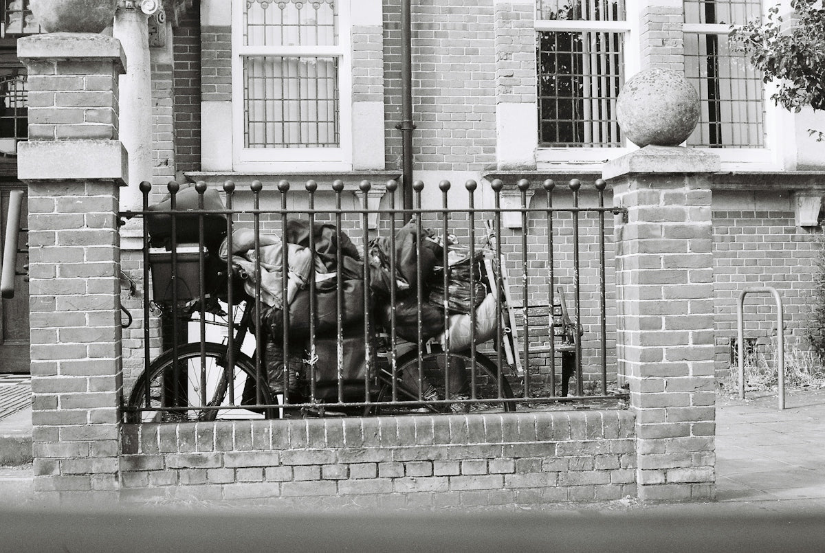 Bicycle parked behind fence in black and white